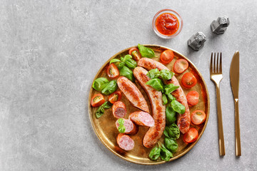 Plate with delicious grilled sausages, tomato and basil on grey background