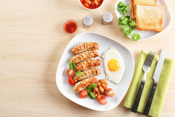 Plate with delicious grilled sausages and fried egg on wooden background