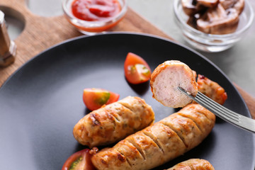 Fork with piece of delicious grilled sausage, closeup