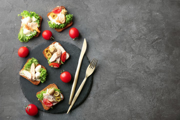 Slate plate with tasty chicken bruschettas on table