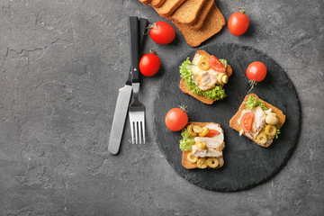 Slate plate with tasty chicken bruschettas on table