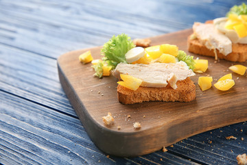 Wooden board with tasty chicken bruschetta, closeup