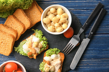 Slate plate with tasty chicken bruschettas and ingredients on table