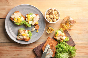 Plate with tasty chicken bruschettas and ingredients on wooden table