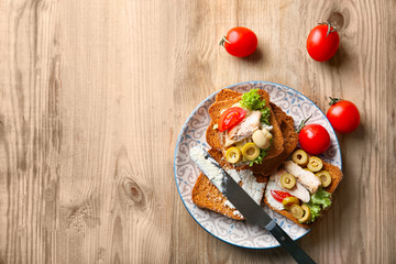 Plate with tasty chicken bruschettas on wooden table