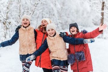 Beautiful teenage girls having fun outside in a wood with snow in winter on a wonderful frosty sunny day. Friendship and active life consept