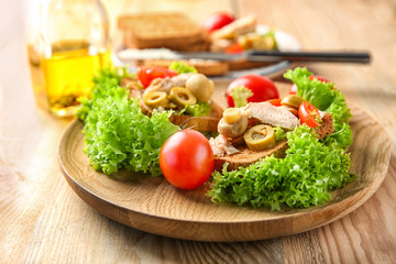 Plate with tasty chicken bruschettas on wooden table
