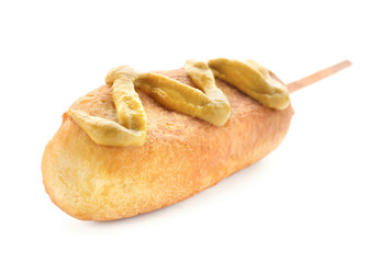 Tasty corn dog with mustard on white background