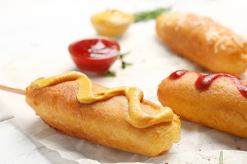 Tasty corn dogs with sauces on table, closeup
