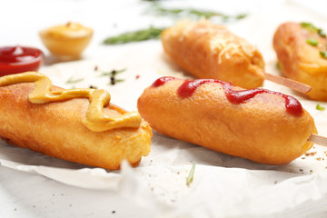 Tasty corn dogs with sauces on table, closeup