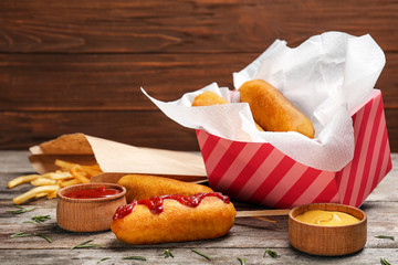 Tasty corn dogs with sauces on table
