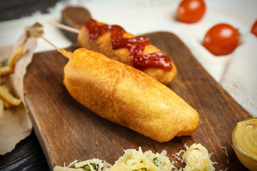 Tasty corn dogs with ketchup on wooden board, closeup