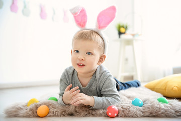 Fototapeta na wymiar Cute little boy with bunny ears and Easter eggs indoors