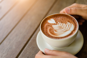 Woman hands holding cup of hot coffee latte cappuccino with heart shaped. Love, Wedding and Valentines day concept.