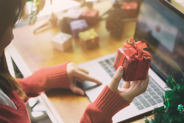 Christmas online shopping side view. woman buyer makes order on laptop with gift box on hand ,Winter holidays sales