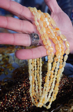 Beads sellerman shows beads on his hand to the customer in a bazar