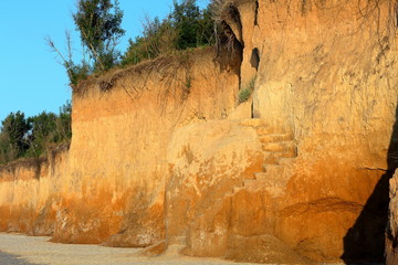 A steep climb up srairs carved in cliff of loamy soil. Staircase, carved in clay crag