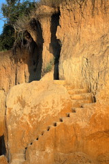 A steep climb up srairs carved in cliff of loamy soil. Staircase, carved in clay crag