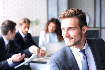 Businessman with colleagues in the background in office.