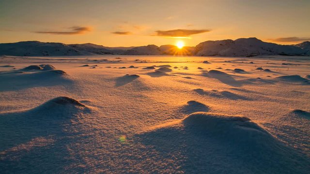 Snowy Arctic tundra at sunset.