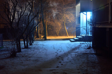 Zaśnieżona ulica w zimową noc oświetlona lapmami.