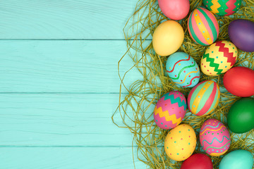 Easter Eggs background. Hand Painted Colorful decorated Eggs on green straw, Blue Wood.Holiday Greeting card. Flat lay