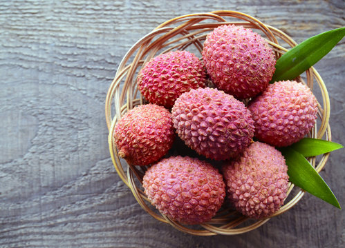 Fresh organic lychees in a basket on old wooden background.Exotic tropical lychee fruits.Raw diet or vegan food concept.Selective focus.