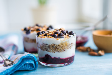 Delicious dessert - yogurt parfait with jam, nuts and currants in a glass