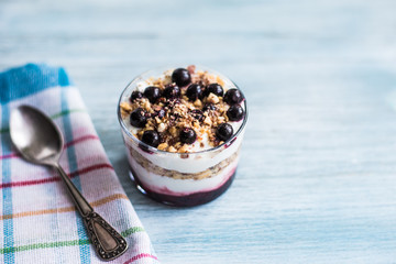 Delicious dessert - yogurt parfait with jam, nuts and currants in a glass