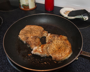 Skillet with pork chops on the stove top.