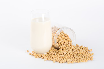 Soy milk in glass with soybeans on white background
