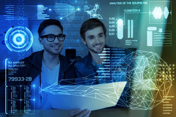 Double check. Cheerful young it men sitting at the table while programming together at night