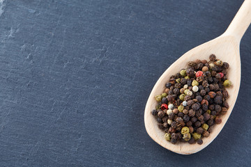 black pepper peas in a spoon on a stone background