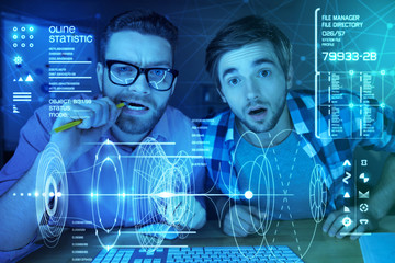 Important task. Concentrated professional IT men sitting at the table and looking at the screen...