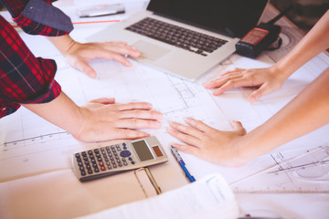 Young asian women architect working on blueprint in the office,engineering work with blueprint,using calculator and laptop,teamwork,construction concept.