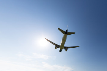 Travel, summer vacation, transportation, aviation - concept, copy space/ Airplane with chassis flying overhead against a spring blue sky, landing mode