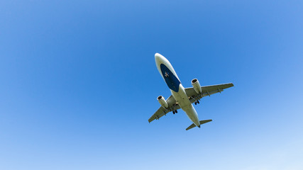 Fototapeta na wymiar Travel, summer vacation, transportation, aviation - concept, copy space/ Airplane with chassis flying overhead against a spring blue sky, landing mode
