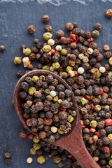 black pepper peas in a spoon on a stone background