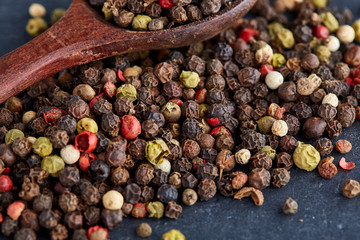 black pepper peas in a spoon on a stone background