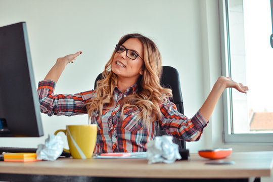 Happy woman sitting at her desk with arms up