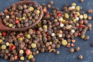 black pepper peas in a spoon on a stone background