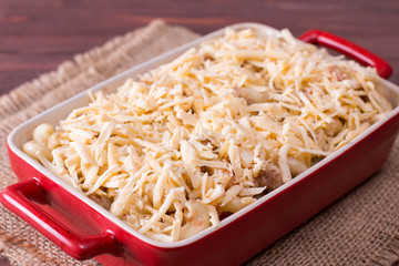 Cheese pasta baked in a ceramic form on background wooden table