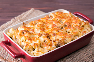 Cheese pasta baked in a ceramic form on background wooden table
