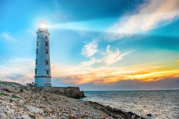 Wall murals Port Lighthouse searchlight beam through sea air at night. Seascape at sunset