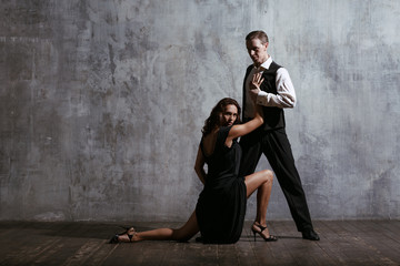 Obraz na płótnie Canvas Young pretty woman in black dress and man dance tango