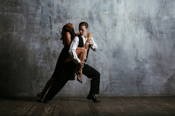 Obraz na płótnie Canvas Young pretty woman in black dress and man dance tango
