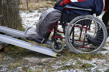 Fototapeta na wymiar Rolling up a disabled person in wheelchair into a country house using metallic guides