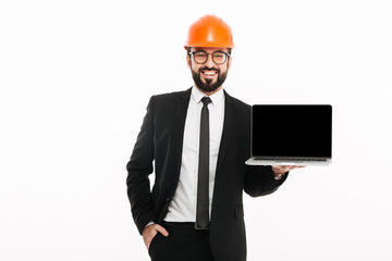 Cheerful builder engineer wearing helmet showing display of laptop