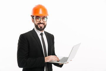 Happy builder engineer wearing helmet using laptop computer.