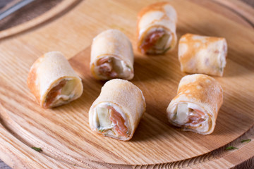 Rolls of thin pancakes with smoked salmon and cream cheese on plate